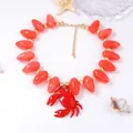 Macro detail of red crab pendant with marble pattern beads on a nautical necklace - Peach