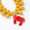 Dettaglio del ciondolo a granchio rosso con grandi perle gialle su una collana da spiaggia - Giallo
