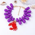 Dettaglio del ciondolo a granchio rosso con perle viola e chiusura a moschettone dorata - Viola