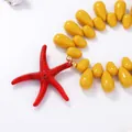 Close-up of red starfish pendant and yellow droplet beads for ocean style necklace - Yellow