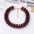 Détail macro du collier en perles marbrées rouges avec entretoises dorées et chaînette - Rouge Foncé