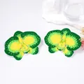 Macro detail of orchid-shaped yellow and green gradient floral earrings on white marble - Green