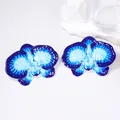Macro detail of orchid flower earrings featuring blue gradient enamel and metal texture - Blue