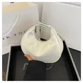 White quilted crescent bag with silver chain strap and metal lock in a gift setting - White