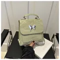 Light green pleated leather handbag featuring a silver metal butterfly and top handle - Green