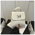 White leather backpack featuring a silver liquid metal butterfly ornament and top handle - White