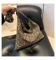 Large leopard print tote bag in soft fabric for women shown on a black sofa - Leopard Brown