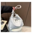 Borsa tote in pelle PU bianca con fibbia a fiocco d'argento e tracolla indossata da modella - Bianco