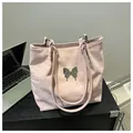 Detail of light pink soft leather tote bag with silver butterfly accent and thin straps - Pink