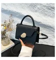 Chic black rectangular crossbody bag with a gold oval buckle and top handle - Black