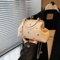 Schicke cremefarbene Muscheltasche mit goldenen Herznieten und Metallrahmen - Weiß