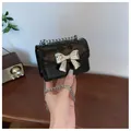 Mini black crossbody bag with silver bow hardware and delicate chain strap - Black