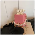 Pink woven bucket bag with pearl handle and golden chain strap for women - Pink