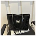 Dettaglio della borsa tote nera con trama stropicciata ed emblema farfalla argento - Nero