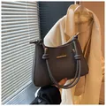 Gray textured shoulder bag with knot handle and gold hardware on minimalist background - Black