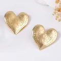 Primer plano de pendientes de corazón vintage dorados con grabados florales y texturas - Dorado