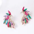 Detailed macro view of gold alloy feather earrings with colorful zircon gemstones - Colorful