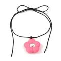 Macroshot van roze hars bloem hanger met strass op zwart koord met een strikje - Roze