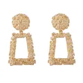 Detail of vintage golden alloy drop earrings with unique embossed lava texture surface - Gold