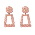 Macro detail of rose gold geometric drop earrings with textured metallic relief finish - Rose Gold