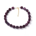 Macro detail of purple marble texture resin cube beads and gold clasp on necklace - Deep purple