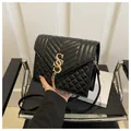 Close-up of black quilted leather crossbody bag with gold metal logo and fringe tassel - Black