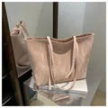 Detalle del bolso tote rosa claro con textura plisada y asas dobles en un expositor - Rosa