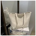 Detalle del bolso tote blanco con textura plisada sobre una pila de libros - Blanco
