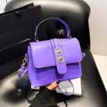 Elegant purple leather crossbody bag with top handle and gold circular metal accents - Purple