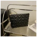 Close-up of black quilted heart-shaped pouch with glossy finish and gold metal zipper - Black