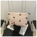 Detail of pink quilted makeup bag featuring black bow embroidery and smooth zipper - Pink