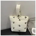 Quilted cream vanity bag with black embroidered bows and single handle design - White