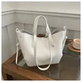 Detail van witte shopper van generfd leer met zijdelingse knoop op een houten tafel - Wit