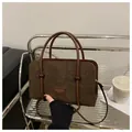 Detail of dark brown corduroy handbag featuring leather handle and a fashion brand tag - Coffee