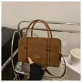 Detail of brown corduroy handbag featuring leather patch logo and round handles - Dark Brown