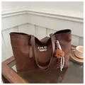 Dettaglio di una borsa tote in pelle scamosciata marrone con orsetto e corda intrecciata - Con Ciondolo / caffè