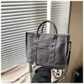Dettaglio della borsa tote in tela grigia con rivetti in metallo e tracolla in tessuto - Grigio