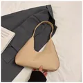 Minimalist beige woven hobo bag with protective metal feet on a blazer suit - Khaki