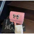 Mini pink crossbody chain bag featuring a silver metal bow accent and faux leather texture - Pink