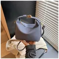 Blue woven fabric crossbody bag with gold buckle and adjustable strap in hand - Blue
