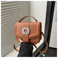 Detailed close-up of brown pebbled leather texture and crystal buckle on luxury handbag - Brown