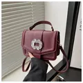 Detailed view of wine red lychee leather handbag with a large sparkling rhinestone buckle - Red