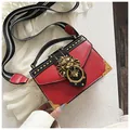Red and black rivet handbag with golden lion head buckle and wide striped shoulder strap - Red
