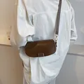 Bolso bandolera marrón oscuro con cierre dorado retro lucido por modelo en estilo chic - Marrón