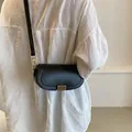 Bolso bandolera negro de media luna minimalista con hebilla dorada puesto en modelo - Negro