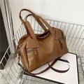 Brown faux leather tote bag with tassel zippers and shoulder strap in a stylish metal basket - Brown