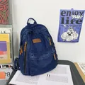 Large capacity denim backpack for women with brown leather patch on a study desk - Dark Blue
