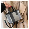 Detail of striped woven tote bag featuring leather handles and gold metal hardware - Black Blue