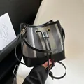 Chic striped bucket bag with black leather trim and drawstring closure in hand - Black Blue