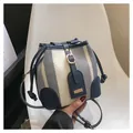 Grey striped bucket bag with blue leather trim and drawstring in a handheld pose - Blue